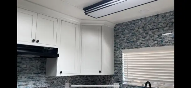 Valle Vista kitchen remodel photo from PL Builders showing finished white cabinet, tile backsplash, countertop, sink, and appliance layout