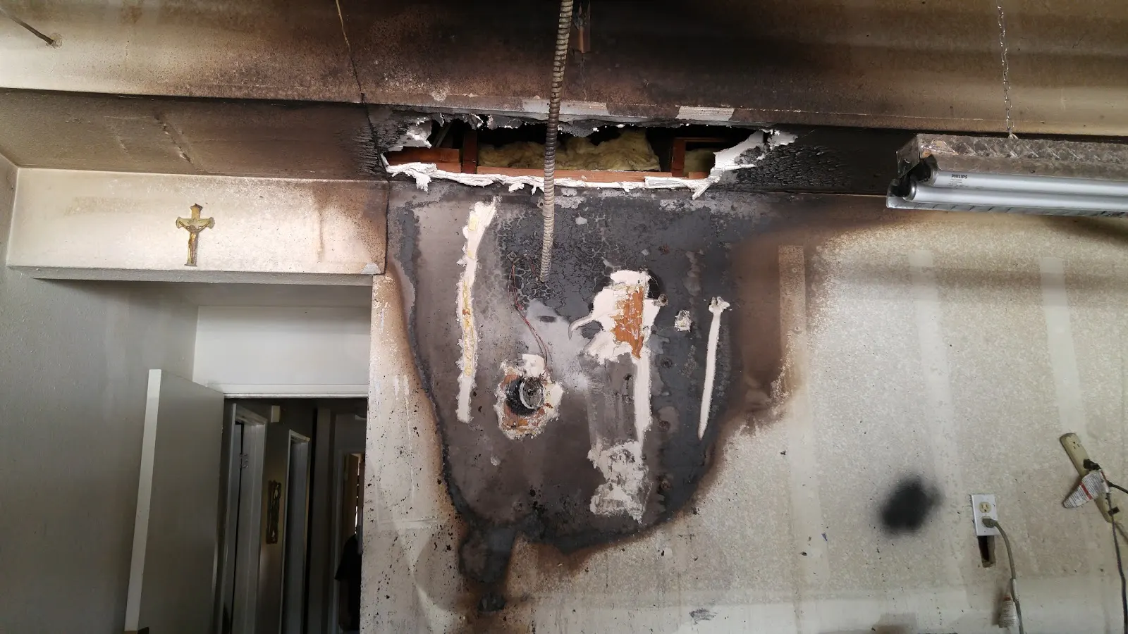Moreno Valley garage fire restoration photo showing burned drywall, smoke staining, and exposed framing documentation
